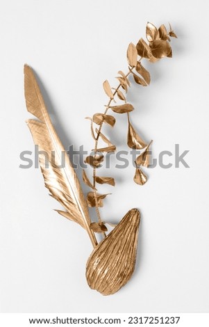 Shiny stylish golden half of avocado, branch with leaves and feather on white background, flat lay. Decor elements