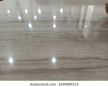 Shiny surface displaying a subtle gray pattern reflecting bright light points, creating a minimalist and clean background suitable for various design applications.