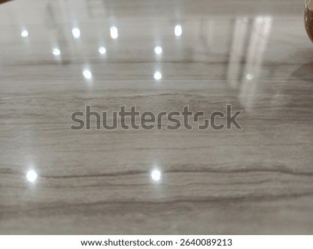 Shiny surface displaying a subtle gray pattern reflecting bright light points, creating a minimalist and clean background suitable for various design applications.