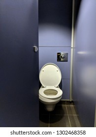 Shiny White Porcelain Toilet With The Seat Up In A Purple MDF Cubicle / Stall With The Door Open In The Toilet / Restroom