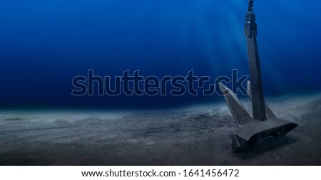Ship anchor underwater on bottom in clean ocean water at anchorage. Marine shipping 
 and diving surveys concept.