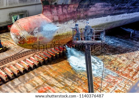 ship cleaning at floating dock of Old forward and Bulbous bow ship before Maintenance on sherry picker car by high pressure water jet in shipyard Thailand