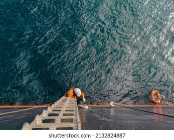 A ship crew is painting draft mark or load line of a cargo ship or bulk carrier