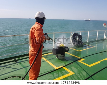 a ship crew is using high pressure washer to wash on ship main deck. Hydro blast.