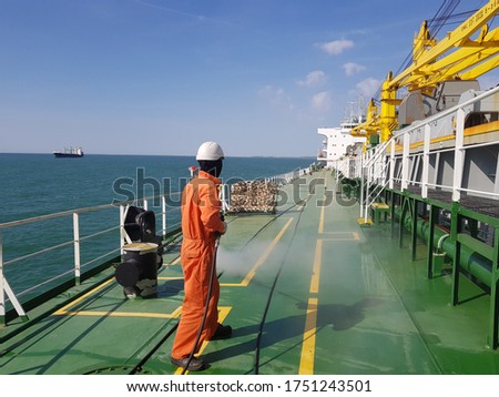 a ship crew is using high pressure washer to wash on ship main deck. Hydro blast.