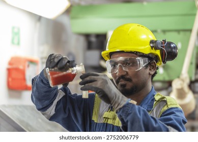 Ship engineer testing coolant water quality of the main engine as part of preventive maintenance onboard a cargo ship.