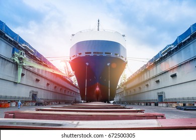 ship in floating dry dock under repair by sandblasting and painting in shipyard