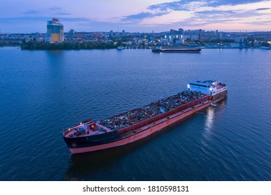 A ship loaded with scrap metal is anchored in the water area of the Dnieper River against the background of the evening city of Dnipropetrovsk. Aerial view