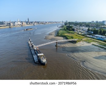 Ship moored at pontoon on the River Scheldt in Antwerp with barge and other boats in the background. City of Antwerp on one side, Linkeroever opposite
