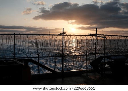 Ship prepared for transiting through piracy risk waters in Gulf of Aden, razor wire all around the ship during sunset