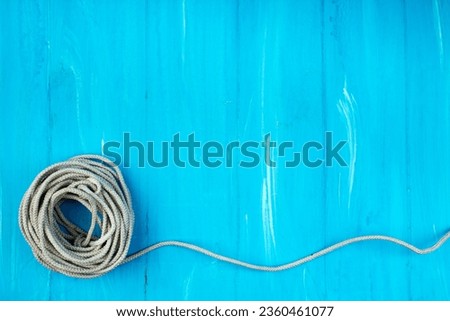 Ship rope knot on blue wooden texture background. Top view