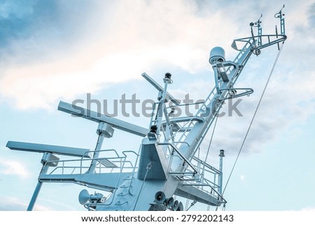 Ship structures, masts, antennas, funnel, ship wheelhouse against the blue sky and clouds. Vessel traveling at ocean.