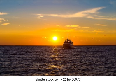 A ship at sunset on the sea horizon. Ship silhouette at sunset. Sunset sea ship silhouette view. Sea sunset ship