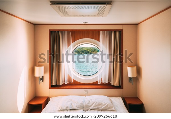 Ship Window In Craft Cabin With Bed. View On\
Sea. Luxury Cabin On Ferry Boat Or Cruise Liner. Sea Cruise\
Vacation Trip Travel\
Concept.