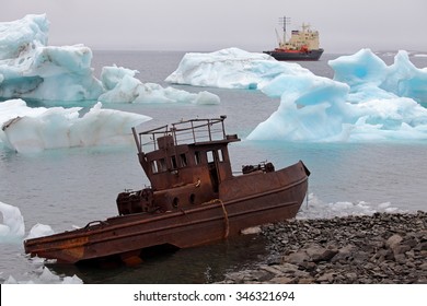 Ship Wreck On Arctic Coast With Icebergs And Icebreaker On Background