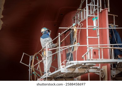 A ship yard worker is working on a ship propeller during dry docking.