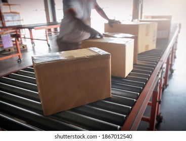 Shipment boxes, parcel. manufacturing and warehousing. cardboard boxes sorting on converyor belt. Worker working in distribution warehouse.  - Powered by Shutterstock