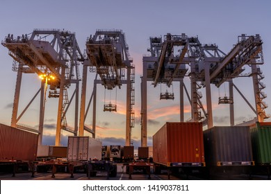 Shipping Container Cranes and Trucks with Sunset Sky in the Port of Oakland. Oakland, Alameda County, California, USA.