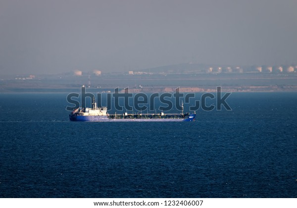 Shipping in Kerch Strait of Black sea of Azov\
sea. Oil tanker river-sea and huge tanks with fuel on shore\
(Taman), ship traffic, cabotage. Marine transportation of petroleum\
products, oil terminal