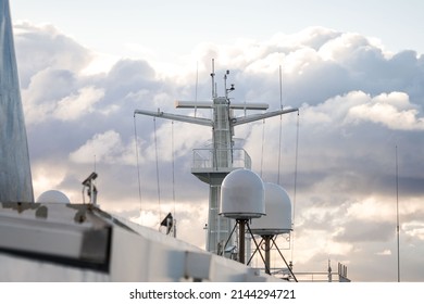 Shipping sea car ferry radar system on boat mast, satellite system with sunset in dramatic sky behind over ocean.