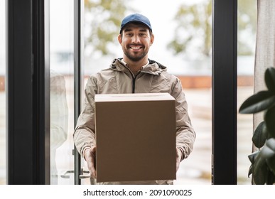 Shipping, Transportation And People Concept - Happy Smiling Delivery Man With Parcel Box At Open Door