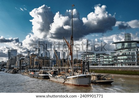 Ships And Boats Anchored On The River Thames In Front Of Modern Office Buildings In The City Of London, United Kingdom