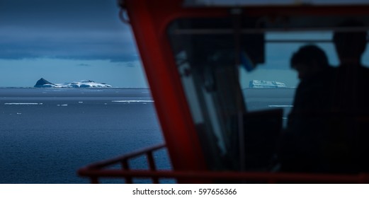 Ships Bridge Silhouetted With Antarctic Icebergs On The Horizon