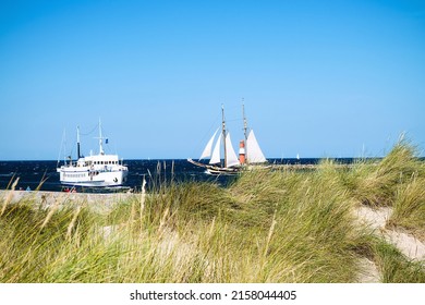Ships at the harbor entrance from the baltic sea to warnemünde and rostock with promenade, lighthouse and dunes.