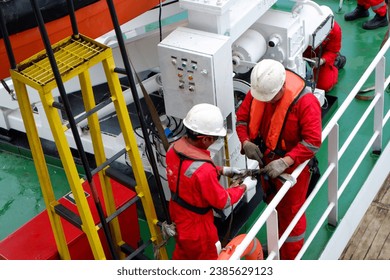 The ship's safety officer is helping the crew to attach the inflatable life vast while the man overboard drill and launch fast rescue boat is being carried out - Powered by Shutterstock