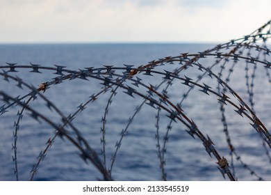 Ship's side fortified with razor wire. Anti piracy protection. HRA, High Risk Areas. Illegal boarding. Ocean background. close up view.