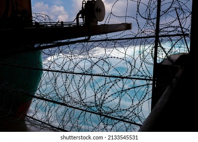 Ship's stern fortified with razor wire. Anti piracy protection is mounted before entering (HRA) Piracy High Risk Areas to prevent illegal boarding. Ship's wake in background.