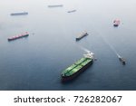 Ships in Straits of Singapore from the height. Big tanker with two helicopter platforms stay on anchor and wait for their turn to enter the port for unloading or loading