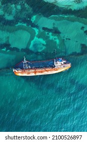Shipwreck, overturned barge, petroleum products leak into the water. Old rusty cargo ship. Drone view.
