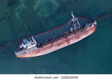 Shipwreck, overturned barge, petroleum products leak into the water. Old rusty cargo ship. Drone view.