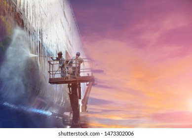 In shipyard image of floating dry Dock worker steam cleaning a old ships hull or side shell wearing safety harness and PPE for safety concept on Twilight tone.