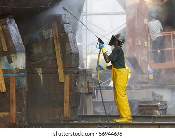 Shipyard Worker Powerwashing A Ship On Drydock