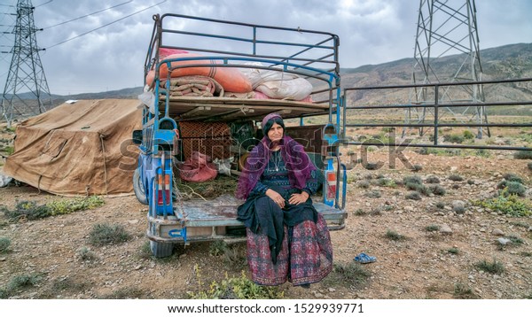 Shiraz, Iran - May 2019: Qashqai nomadic woman\
sitting at the back of her old car. The Qasqhai are nomadic people\
living in temporary\
villages.