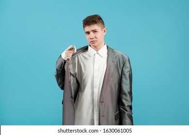 The Shirt And Jacket Of An Adult On A Young Guy Look Ridiculous. Young Man Showing, That His Clothes Is Too Big For Him