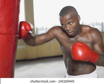 Shirtless African American boxer punching bag - Powered by Shutterstock