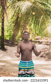 Shirtless African American Male Traveler In Shorts Looking At Camera And Juggling Fruits On Weekend Day On Tropical Beach