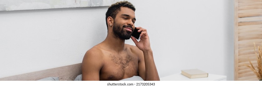 Shirtless African American Man With Dyed Hair Talking On Mobile Phone In Bedroom, Banner