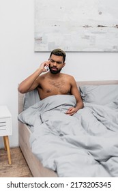 Shirtless African American Man With Dyed Hair Talking On Mobile Phone In Bed