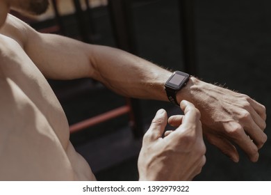 Shirtless athlete using smartwatch while resting workout. Fitness gadgets concept. Space for text. Copy space - Powered by Shutterstock