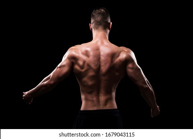 Shirtless big bodybuilder posing on black background from behind