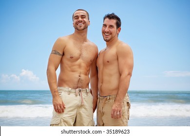Shirtless gay couple standing on a beach