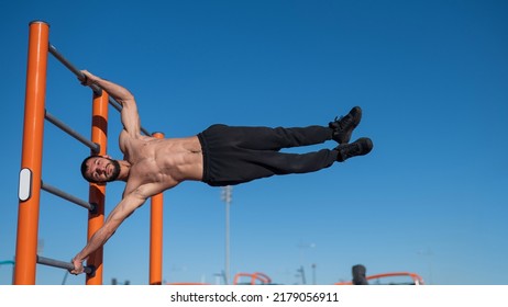 Shirtless man doing human flag outdoors.  - Powered by Shutterstock