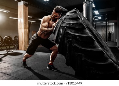 Shirtless man flipping heavy tire at gym - Shutterstock ID 713015449