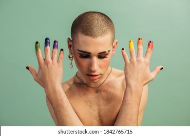 Shirtless man with gay pride flag colors on his fingers. Gender fluid male with makeup and lgbt rainbow colored fingers.