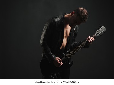 Shirtless Man in leather jacket Playing Guitar