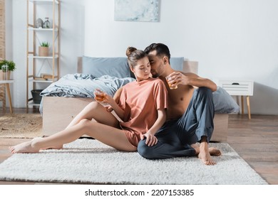 Shirtless Man In Pajama Pants And Sexy Woman In T-shirt Sitting On Floor In Bedroom With Tea Cups